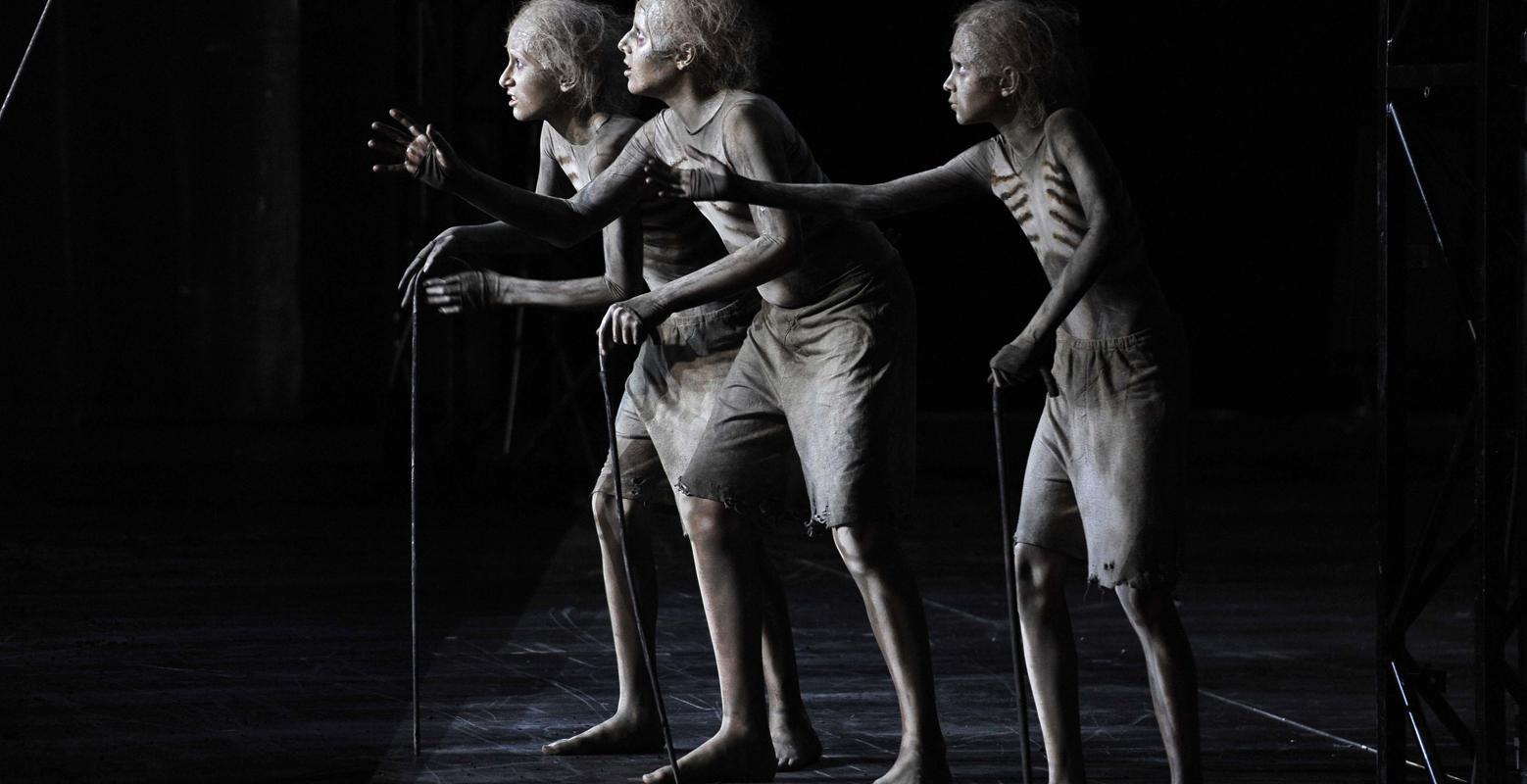 Three skeletons with walking sticks holding out their hands in ENO's The Magic Flute