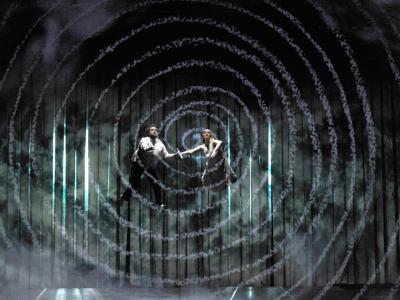 A man and woman suspended in mid-air above the stage in ENO's The Magic Flute