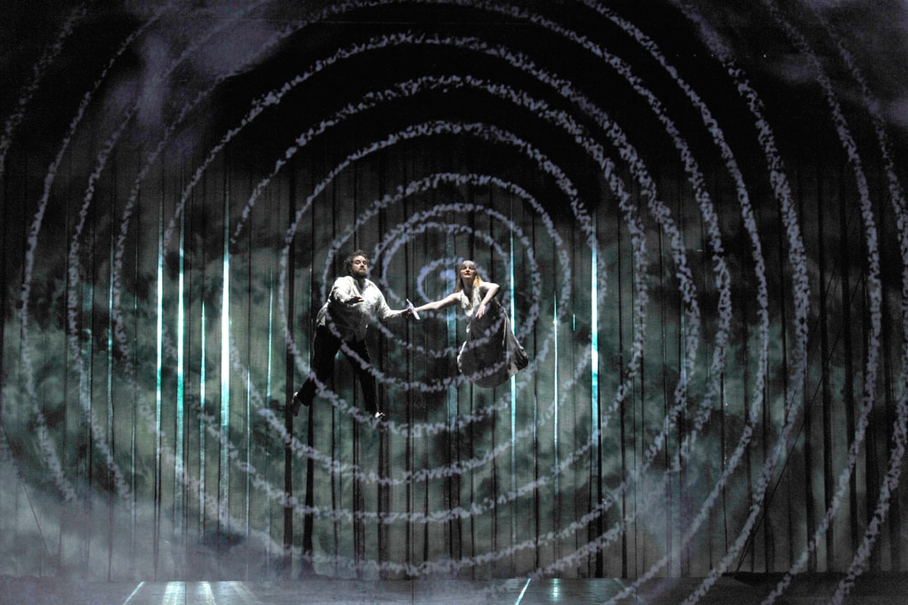 A man and woman suspended in mid-air above the stage in ENO's The Magic Flute