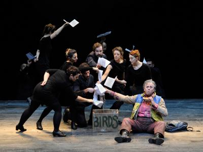 Group of people wearing black placing white pages into a box labelled 'birds' in ENO's The Magic Flute