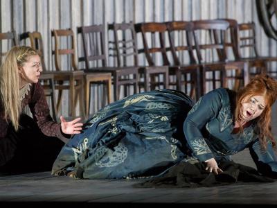 two women on stage on the floor with row of chairs behind them in Bellini's Norma