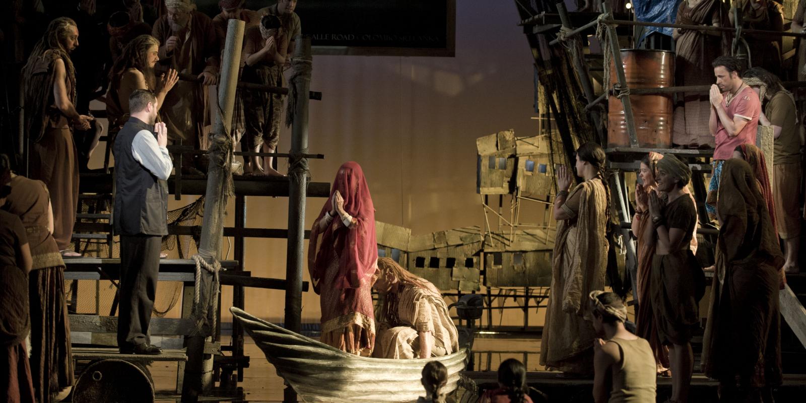 people praying surrounding a praying woman on a boat in ENO's The Pearl Fishers