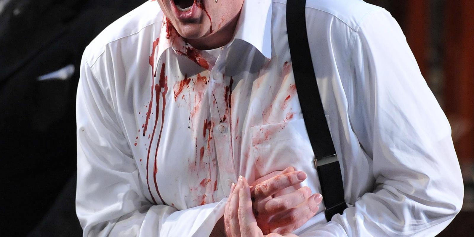 man on stage with blood on his white shirt in Rigoletto