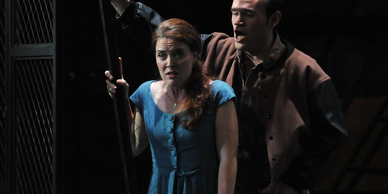 man standing behind woman in blue dress in ENO's Rigoletto