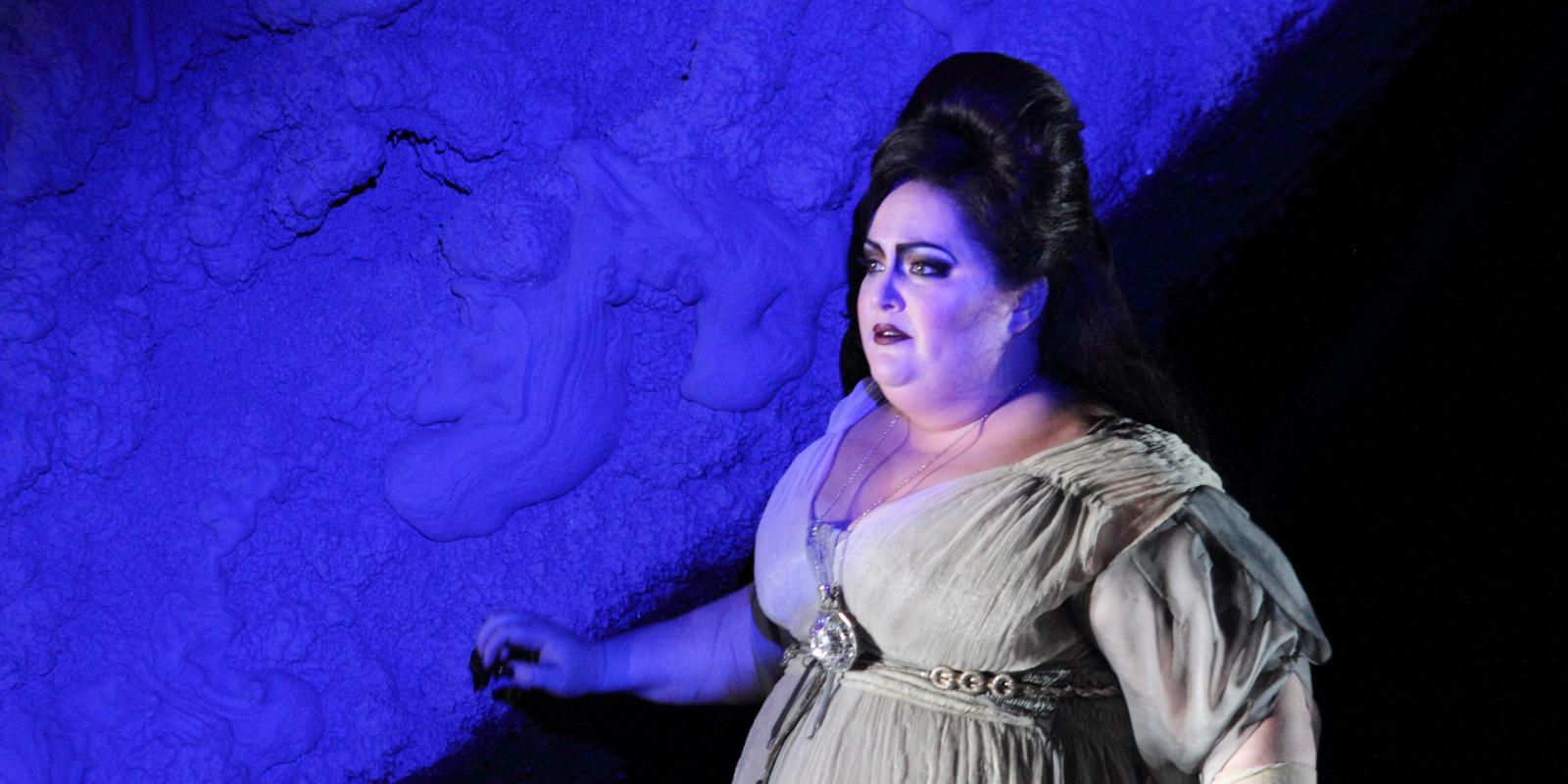 Heidi Melton standing next to a blue wall in ENO's Tristan and Isolde