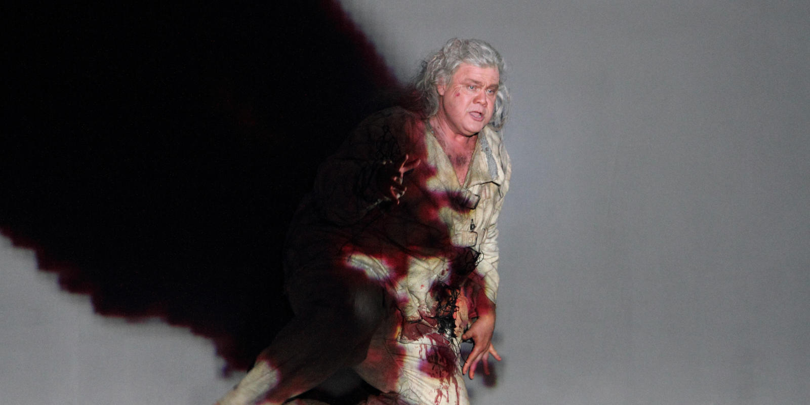 man performing on stage in blood stained costume in Tristan and Isolde