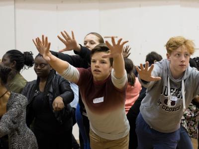 group of actors rehearsing with arms outstretched