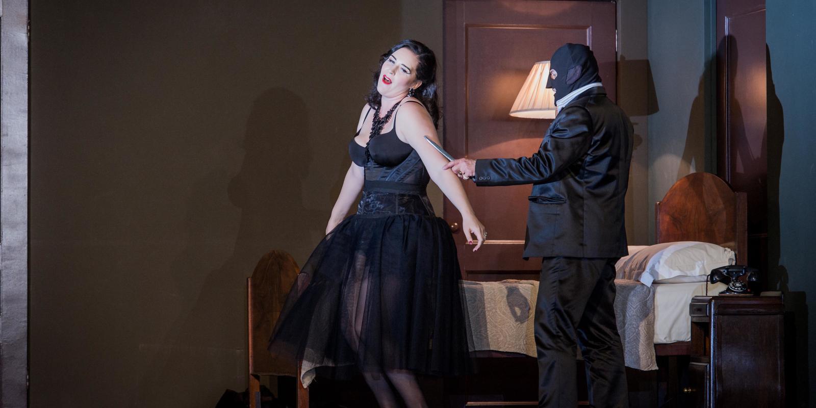 man in mask holding a knife to a woman in black dress in Don Giovanni
