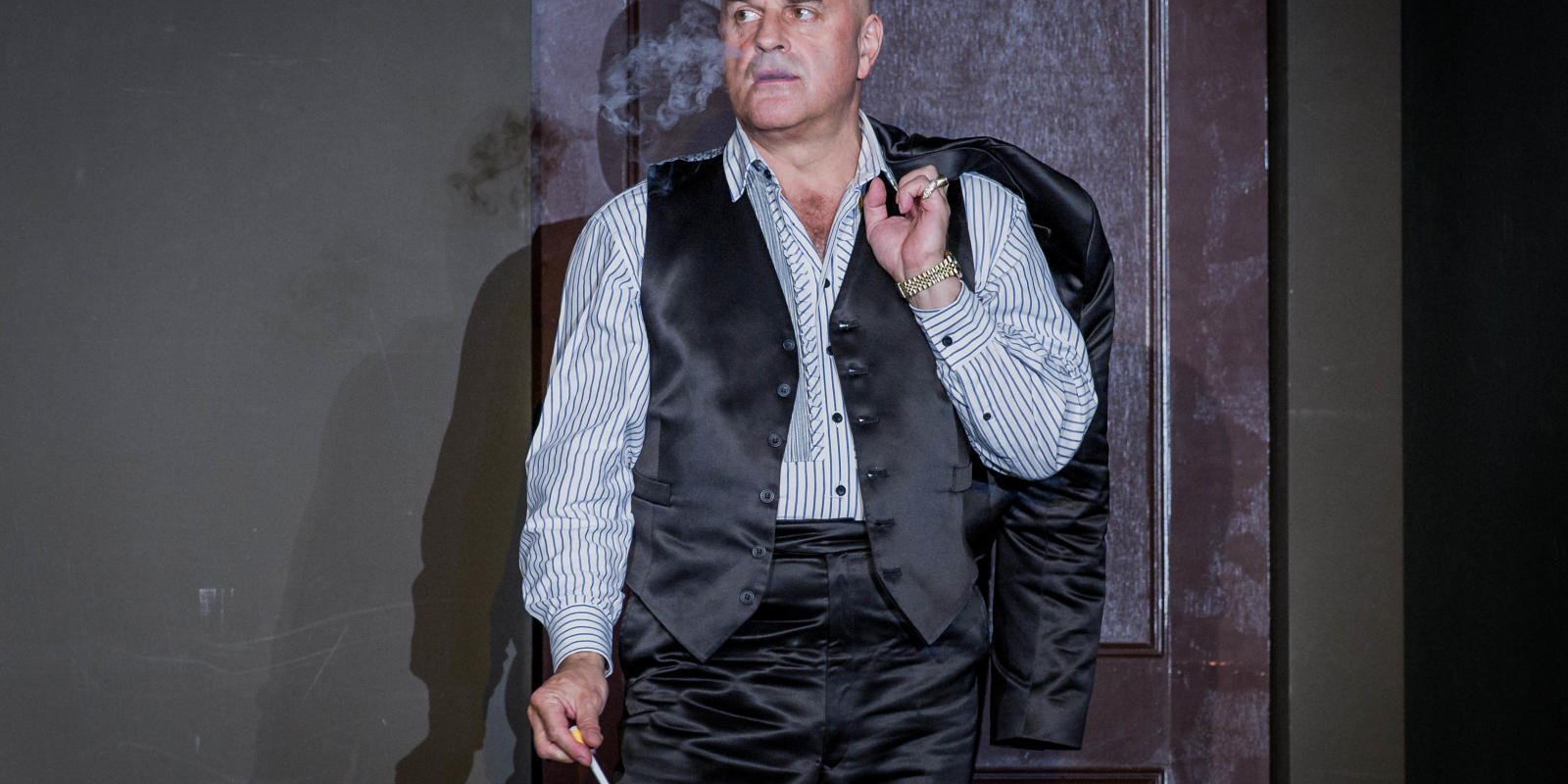 man smoking with jacket on his shoulder in ENO's Don Giovanni