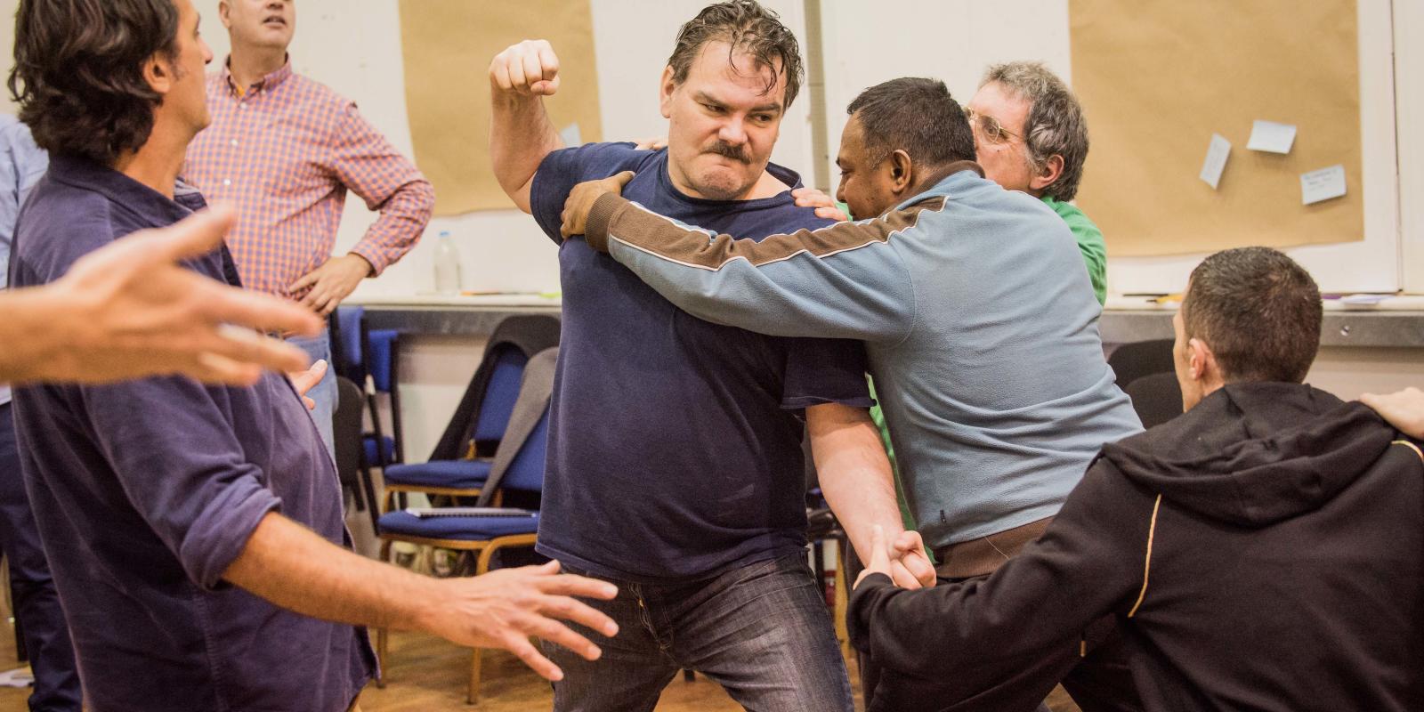 Man throwing fist being held back during rehearsals for the Don Giovanni project