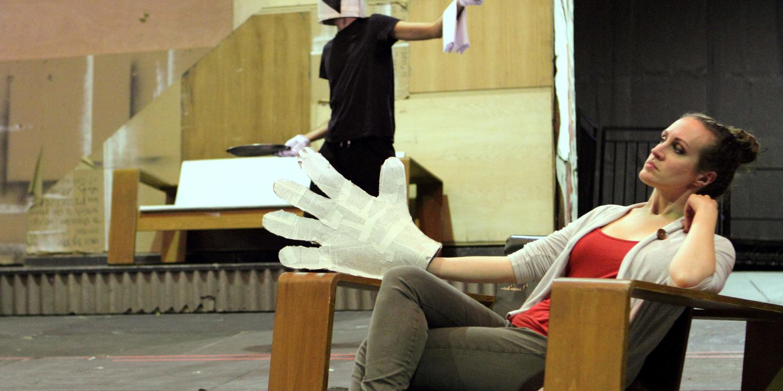 woman sitting down with giant white glove in Lulu rehearsals