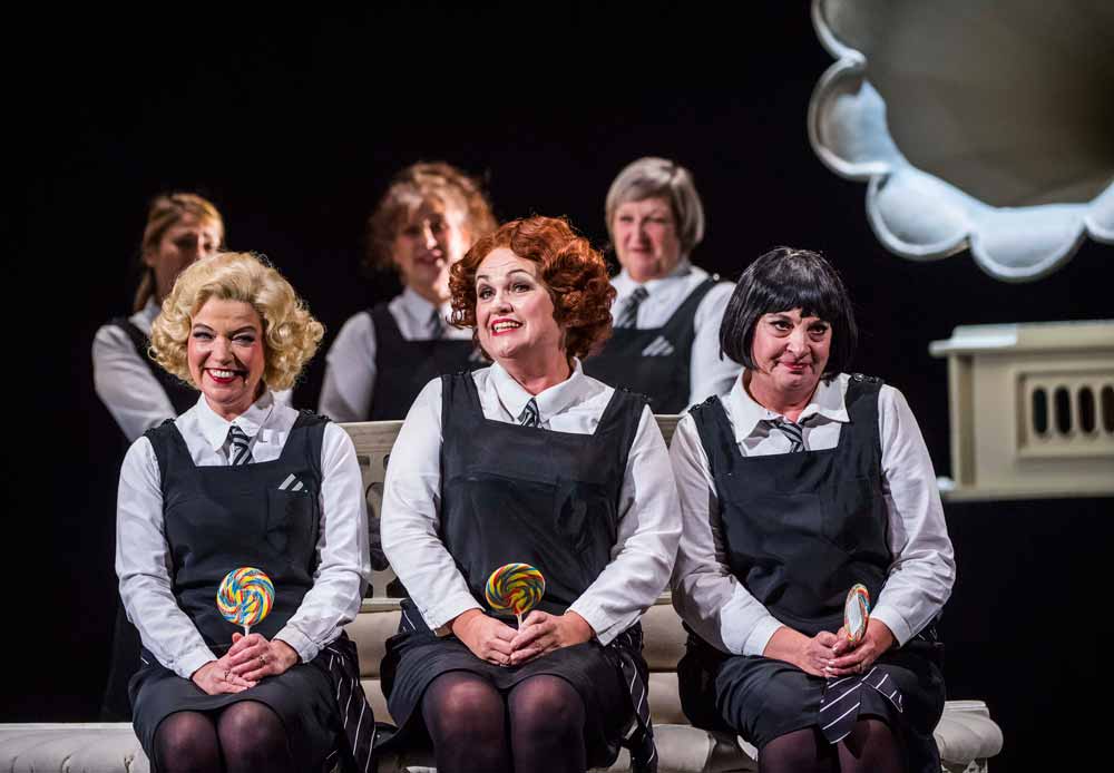 three women in school uniform sat down holding a lollypop