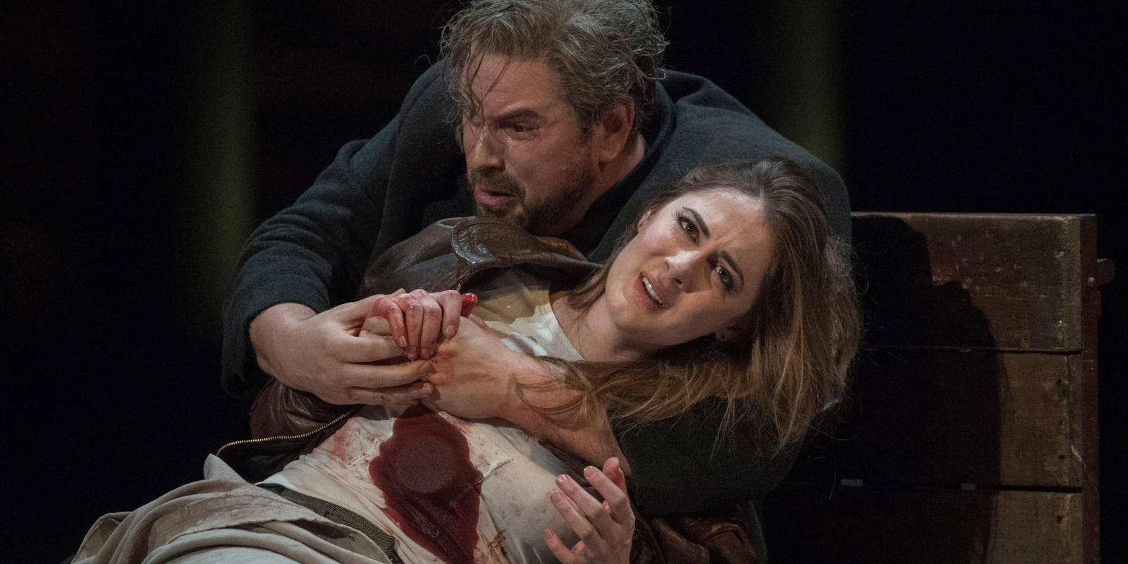 woman with fake stab wound and man holding her performing for rigoletto on stage