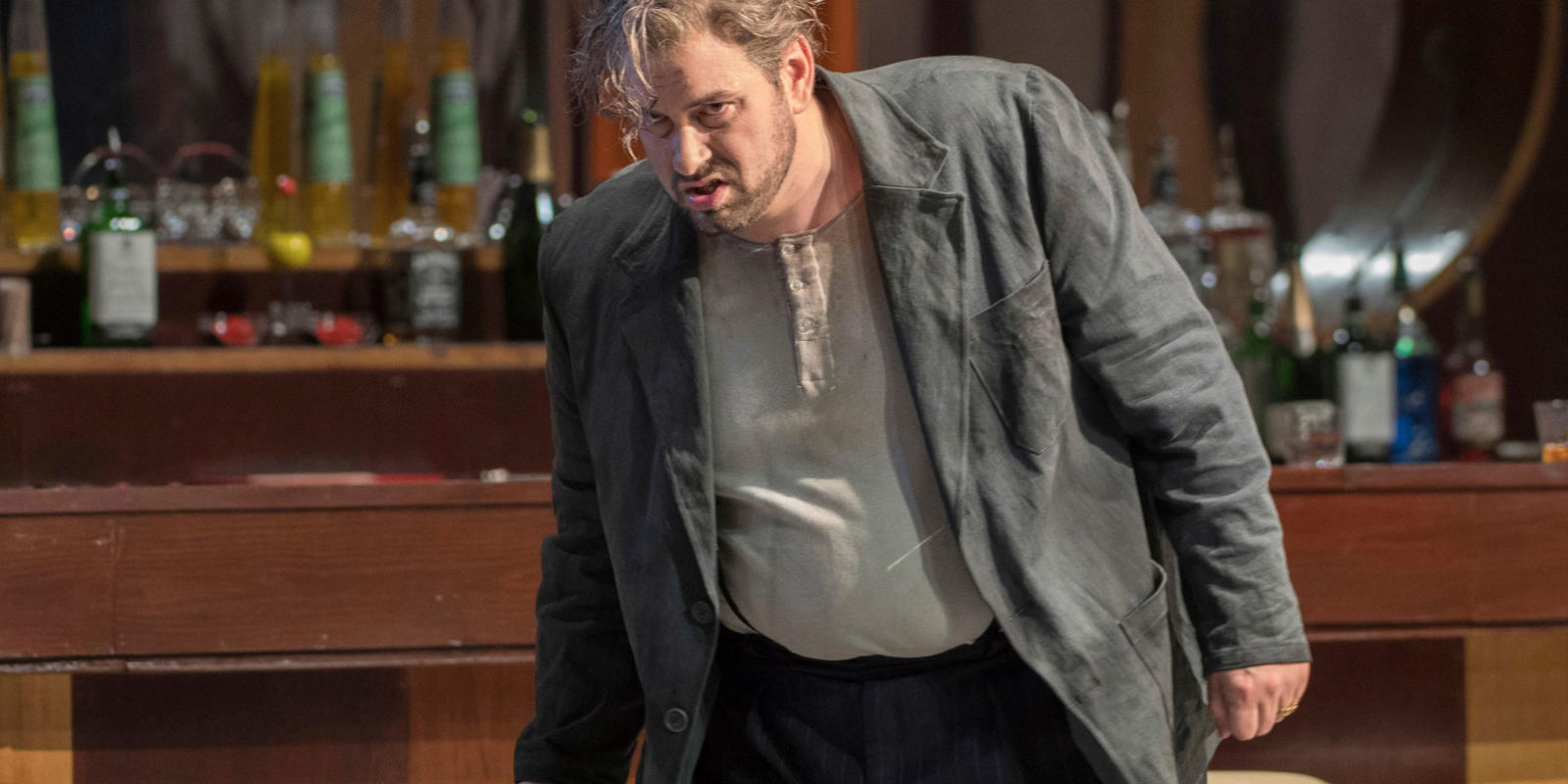 Nicholas Pallesen looking drunk in a bar from ENO's Rigoletto