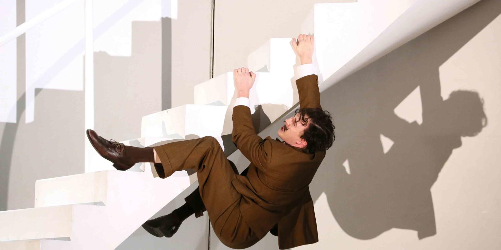 a man holding onto the stairs, falling
