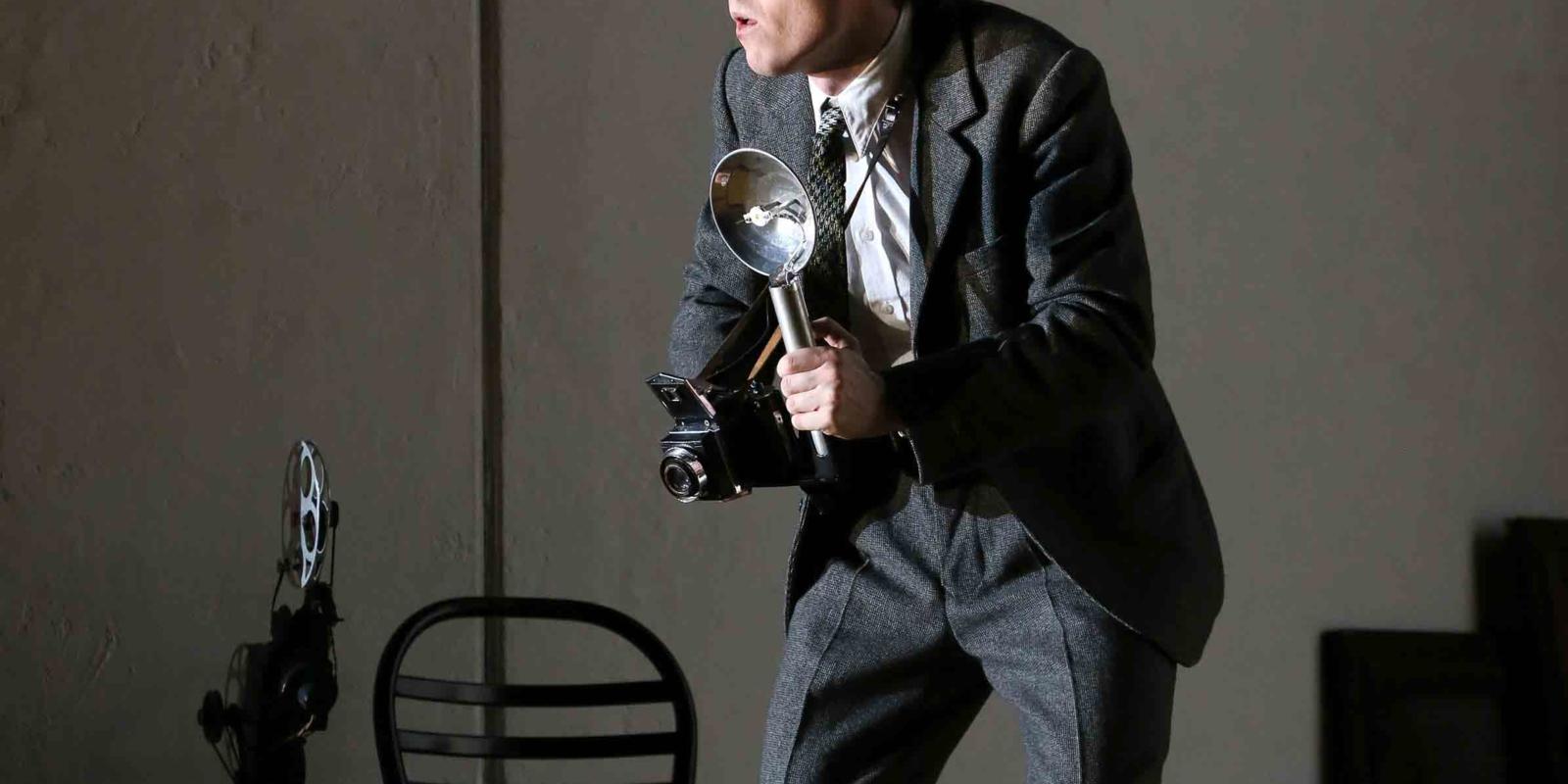 a man in a suit, holding a camera