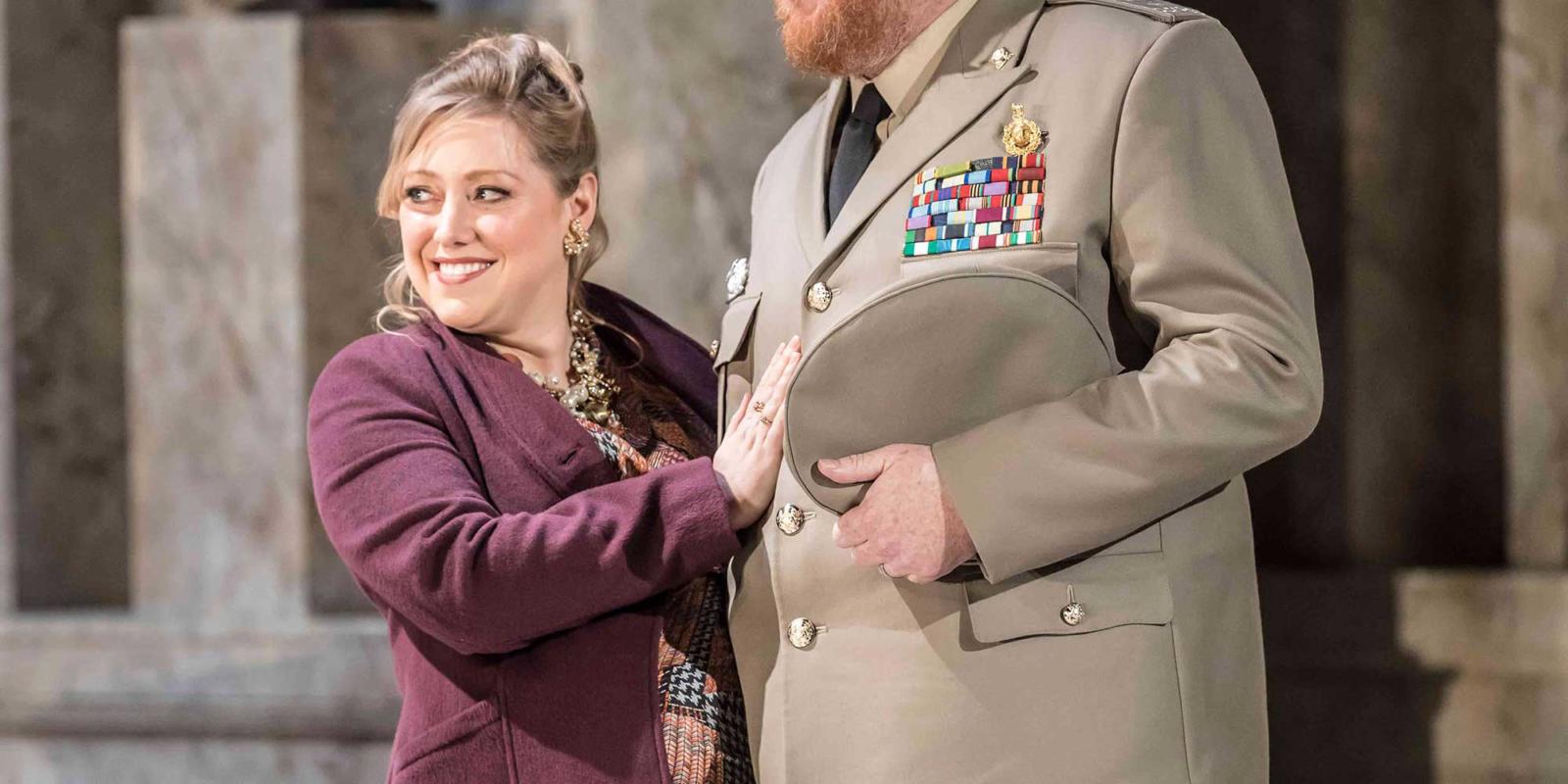 Woman in red jacket standing with hand on a man in military clothes in the Winter's Tale
