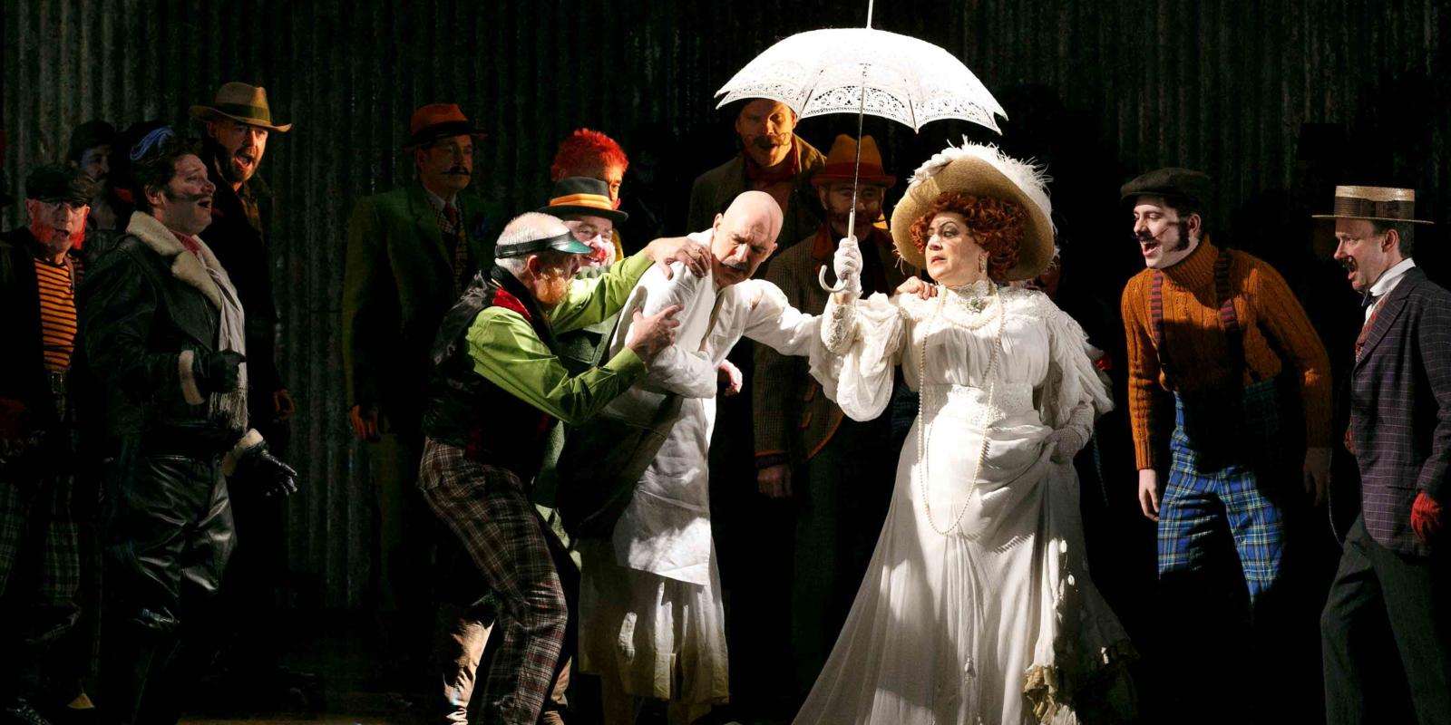 women in white holding a white umbrella with a man in white being accosted by a group of people