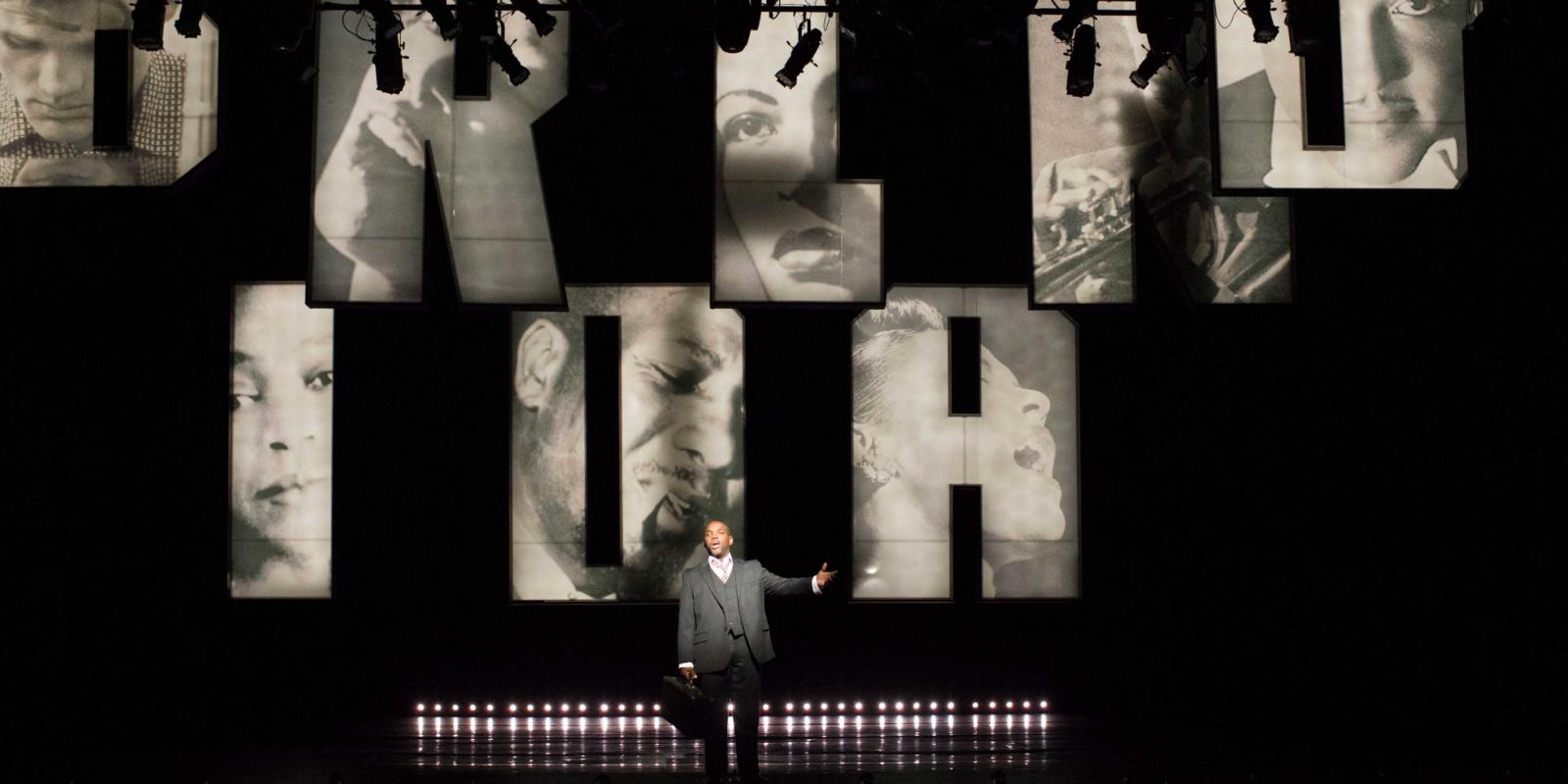 a man singing with black and white images projected behind