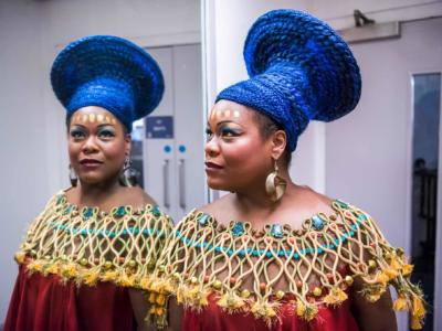 woman performing in aida standing by a mirror backstage in full African makeup and costume