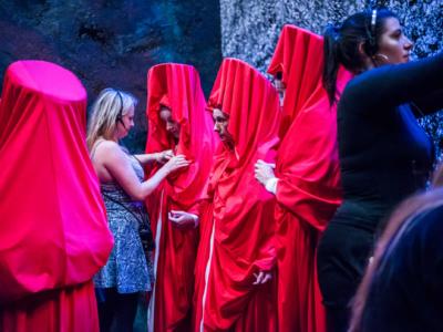 sound woman dressing cast in red cloaks backstage of Aida