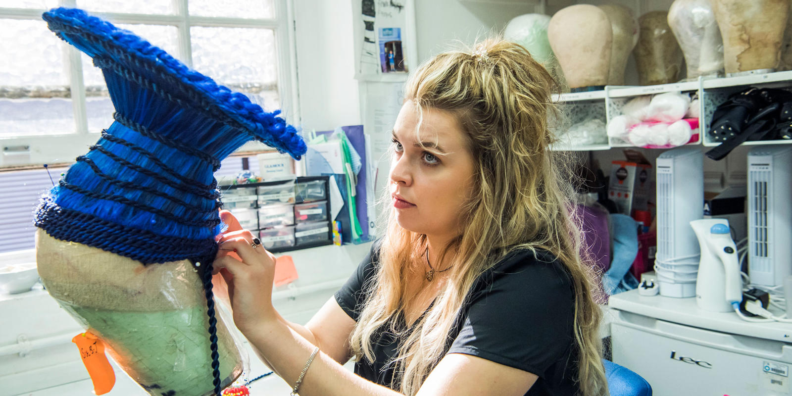 Woman creating a blue headset for Aida in ENO's costume department