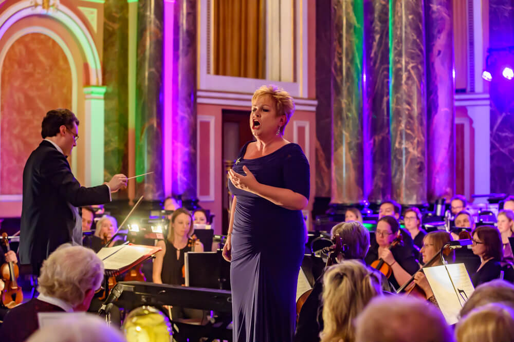 Susan Bullock singing to guests in front of an orchestra at ENO's Gala Dinner