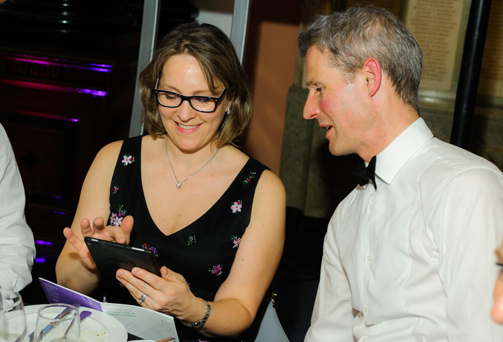 Man and woman looking at a tablet during ENO's Gala Dinner