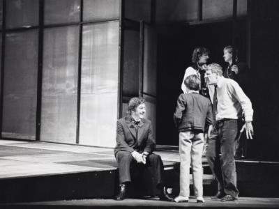 a black and white image of a group of people chatting on set