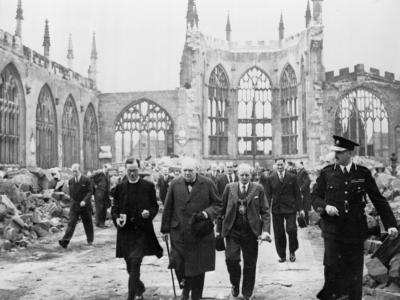 Winston Churchill walking through the ruined nave of Coventry Cathedral, England, after it was severely damaged in the Coventry Blitz of 14–15th November 1940
