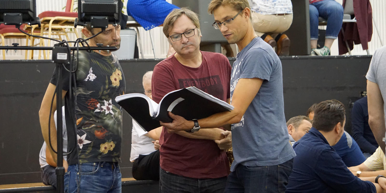 three men looking at a script