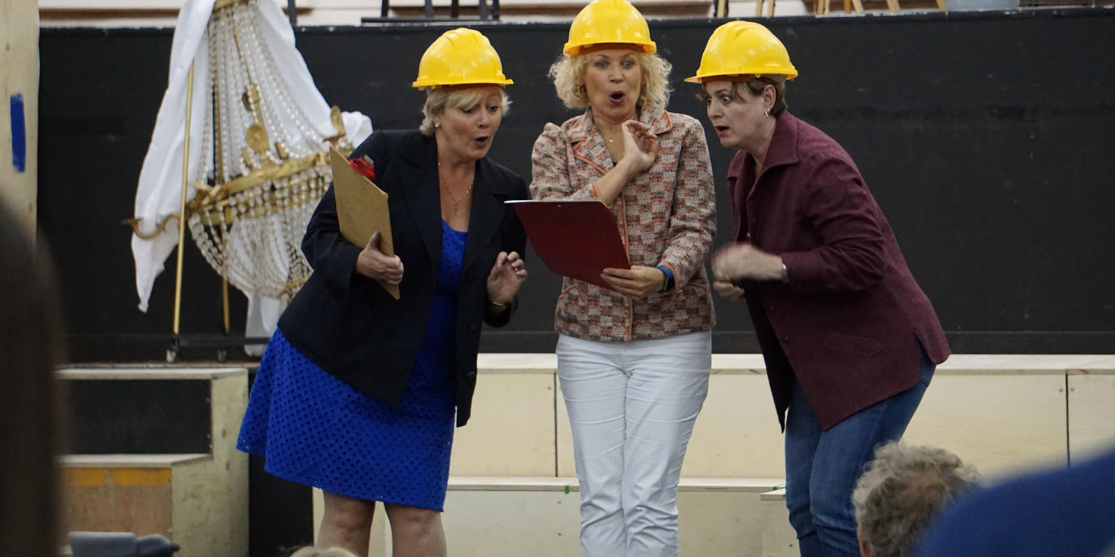 three women in hard hats looking at a clipboard