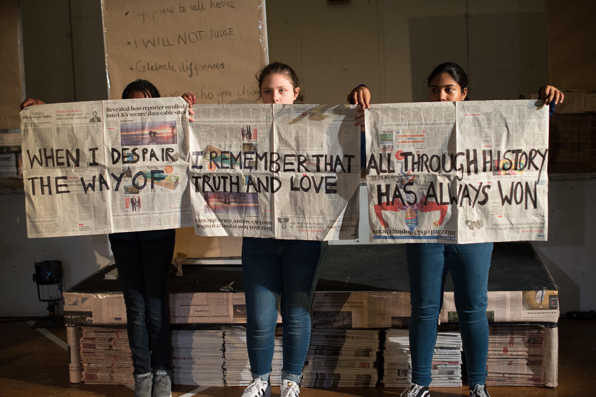 ENO's youth programme participants holding up Gandhi's message written on newspapers