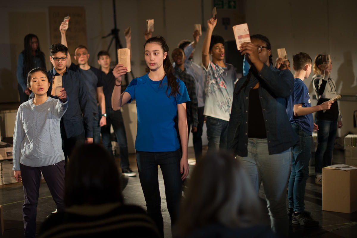 Group of young people addressing the audience while holding up pages of an open book