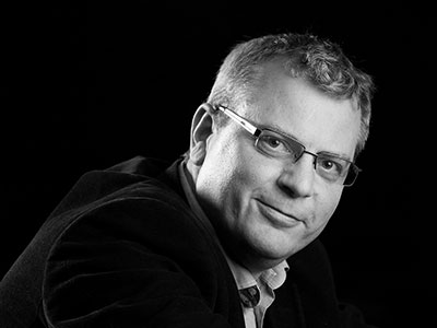 Stuart Stratford wearing glasses, leaning forward looking to camera