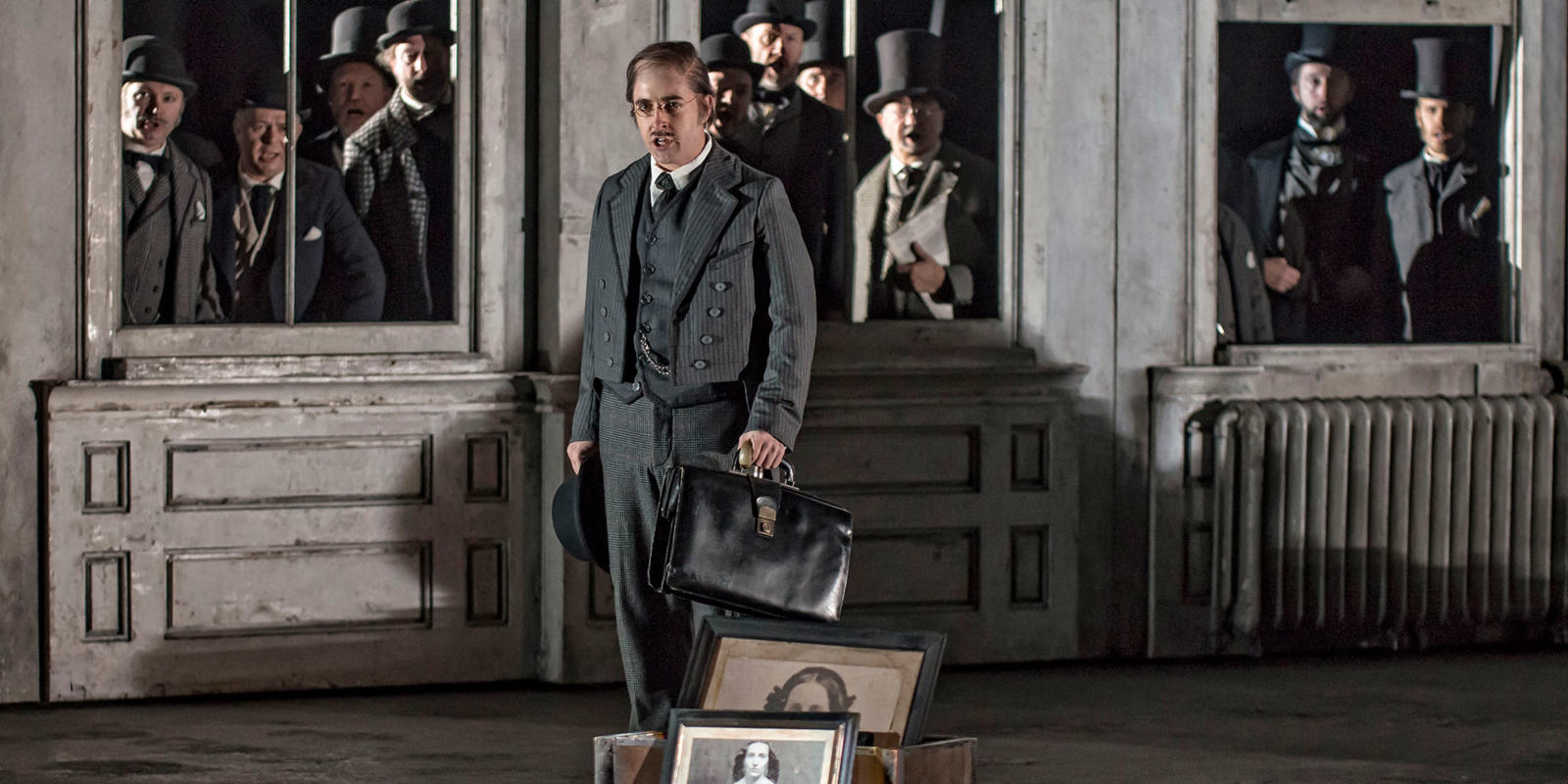 person with a series of portraits, dressed in a 3 piece suit