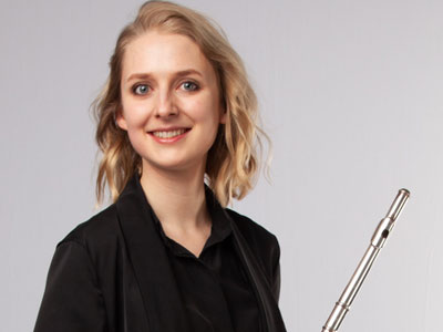 Claire Wickes smiling to camera holding her flute