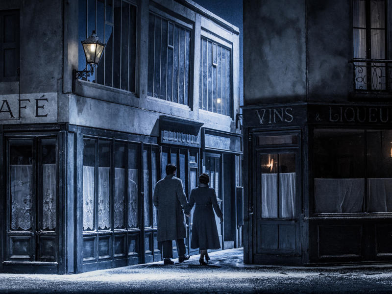 Main roles from La Bohème walking down a small dark alleyway holding hands