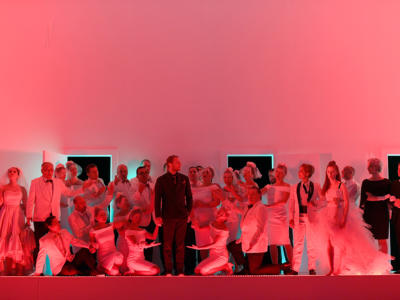 a group of people dressed in white with a pink backdrop