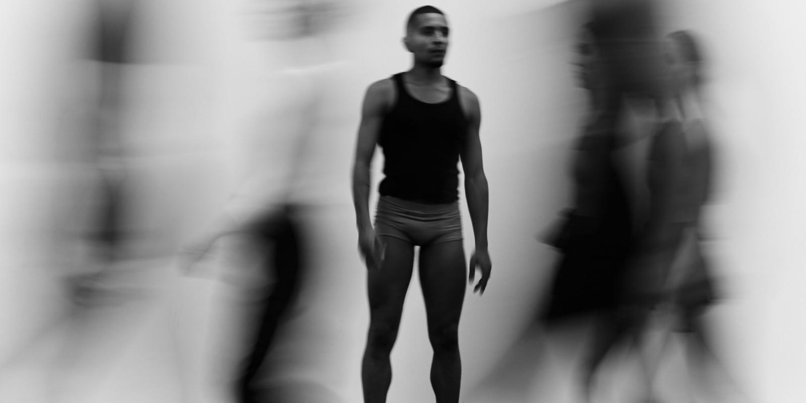a man standing with blurred people moving around him