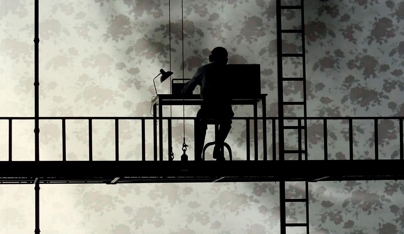 2 versions of Orphée work as desks, silhouetted agaisnt a projected backdrop.
