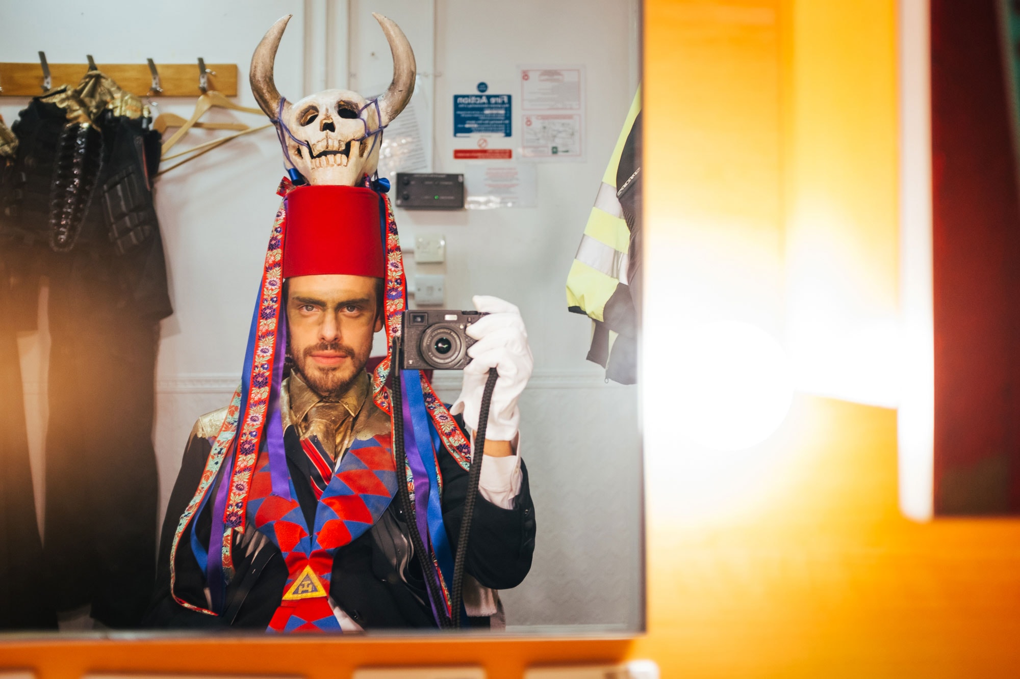 man taking a picture in the mirror: wearing a red hat and skull
