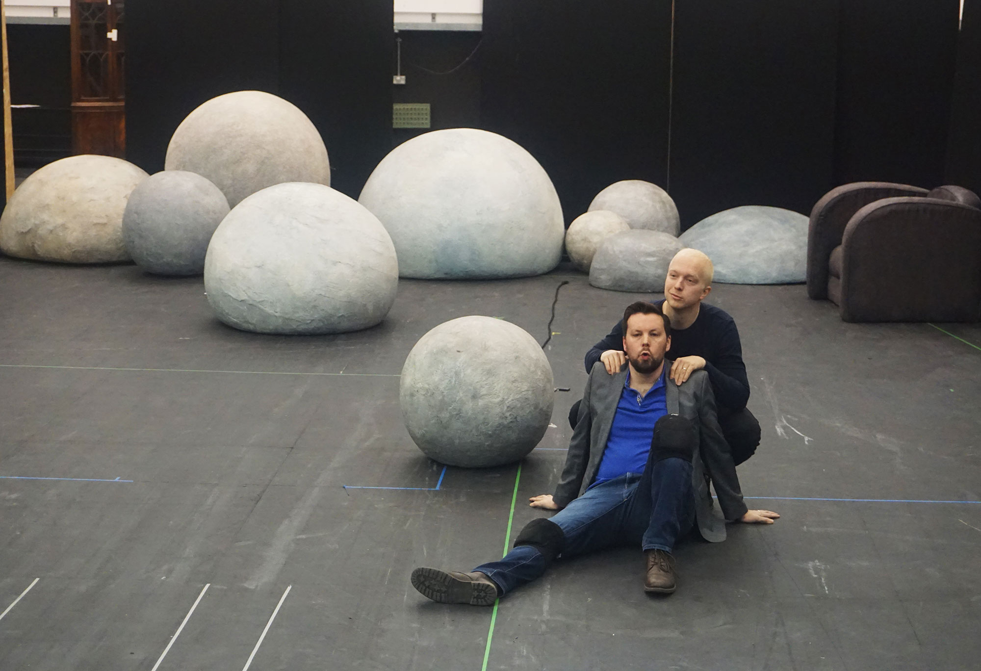 two men sat on floor surrounded by white blobs rehearsing on stage
