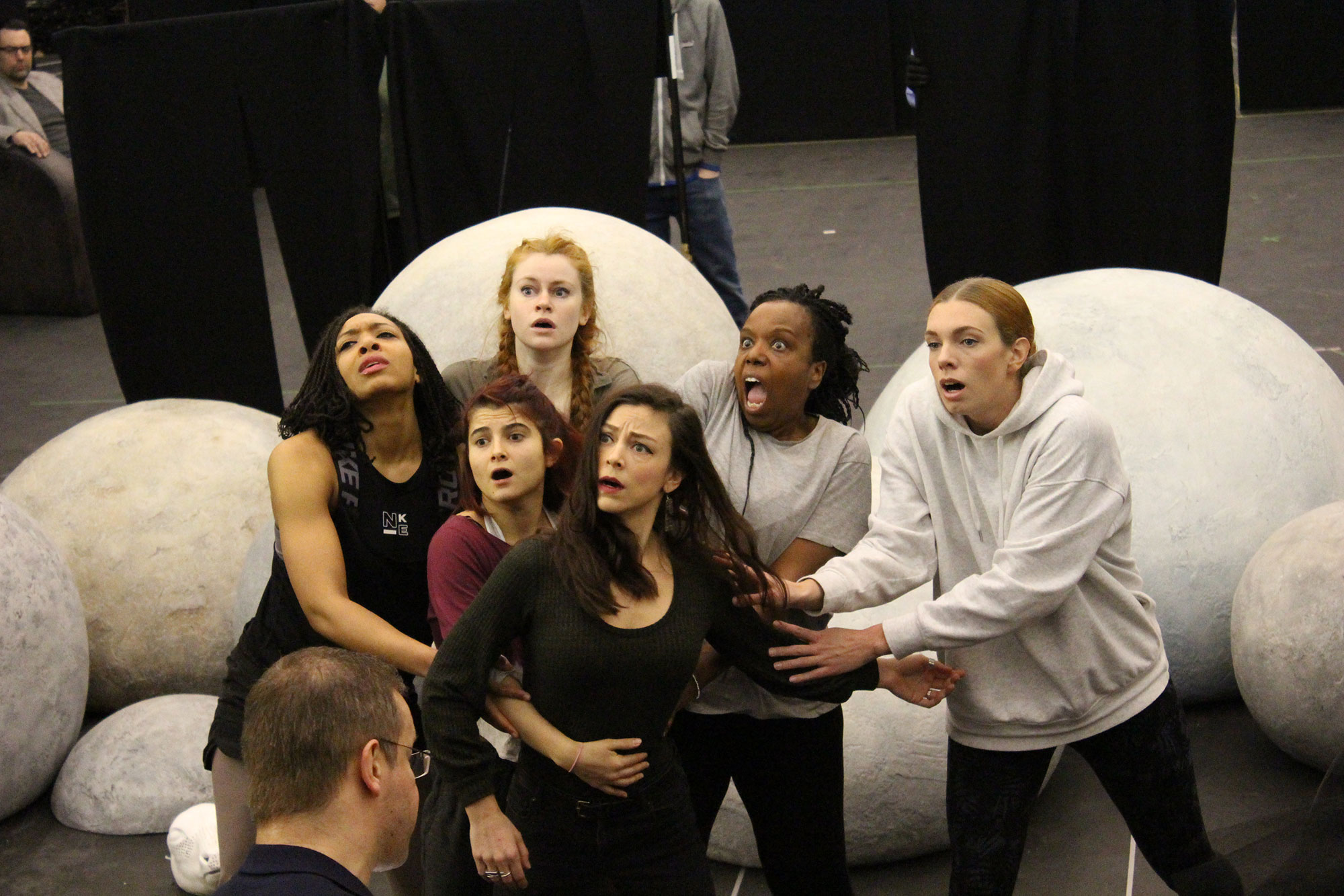 group of women looking surprised surrounded by grey spherical props