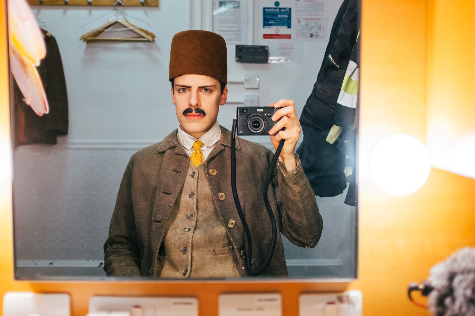 man taking a picture in the mirror: wearing a workers suit and hat
