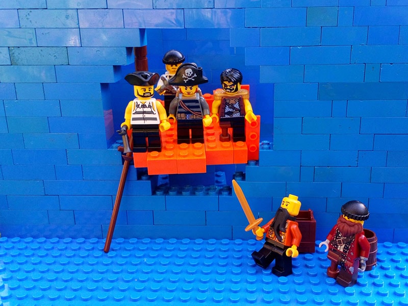 lego pirates on a lego ship coming through a lego wall
