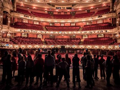 Group of people on the stage of the London Coliseum looking out to an empty auditorium