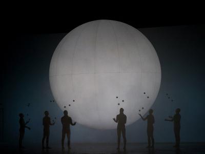 six people stood with their arms out by a giant moon