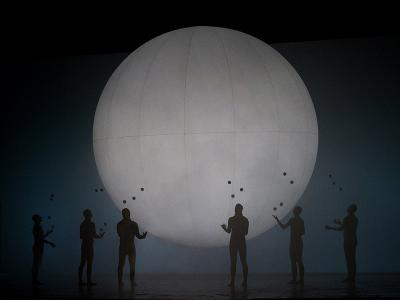 A group looking up toward a large white globe in ENO's Breathe