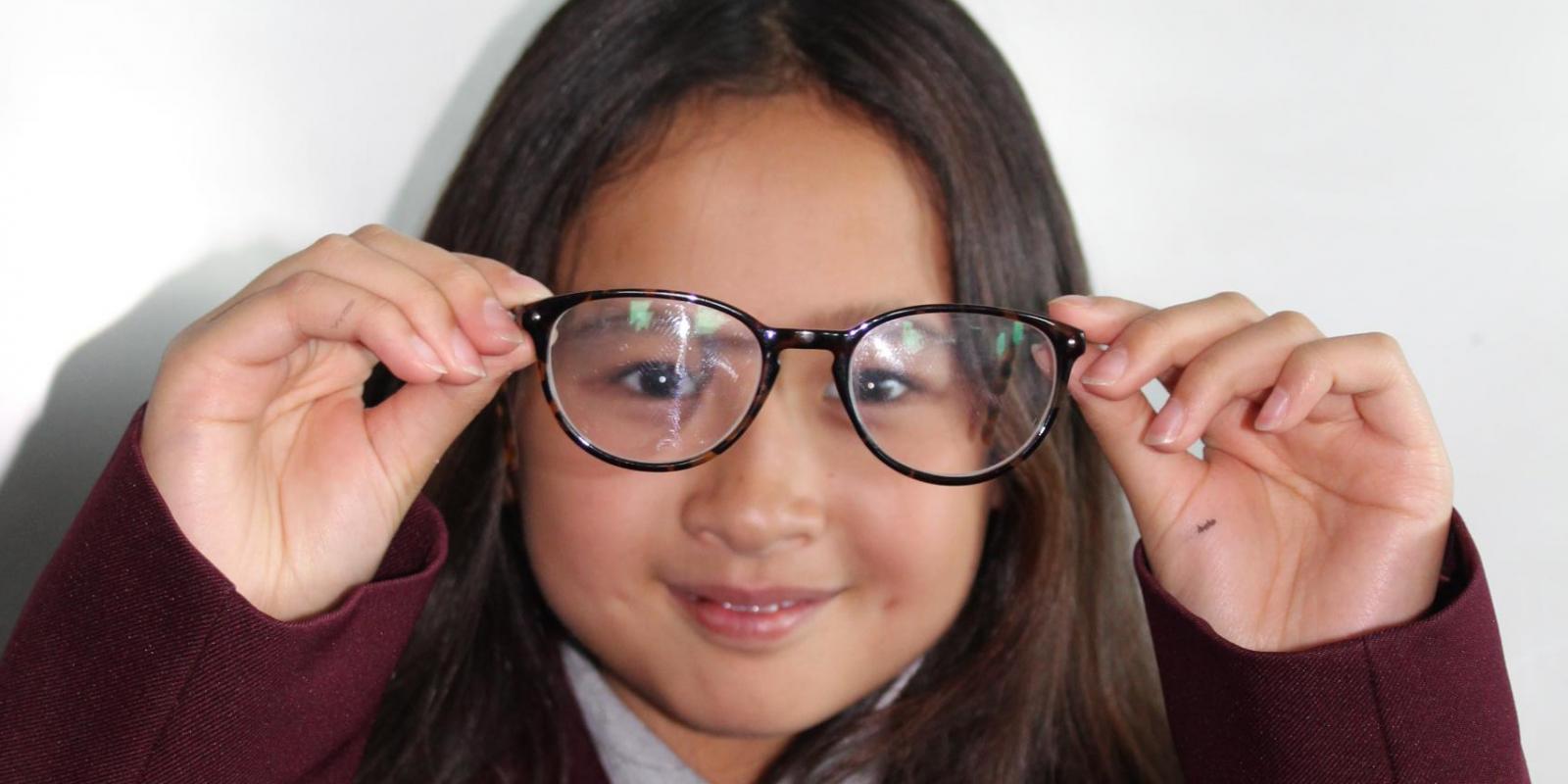 Schoolgirl holding glasses up to face
